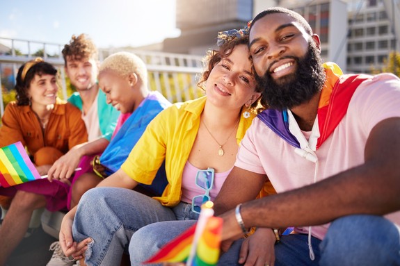 A decorative image of people of mixed ages, genders, and ethnicities. Some are carrying pride flags.